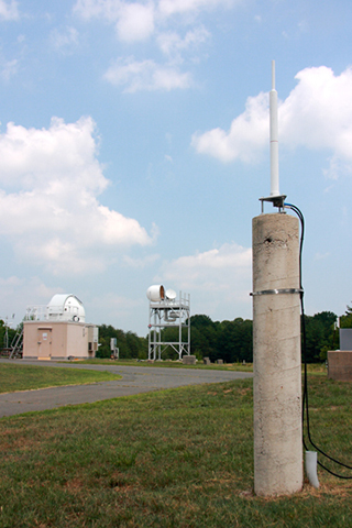 DORIS antenna mounted on a pillar monument. The building in the background to the left is the NGSLR system.